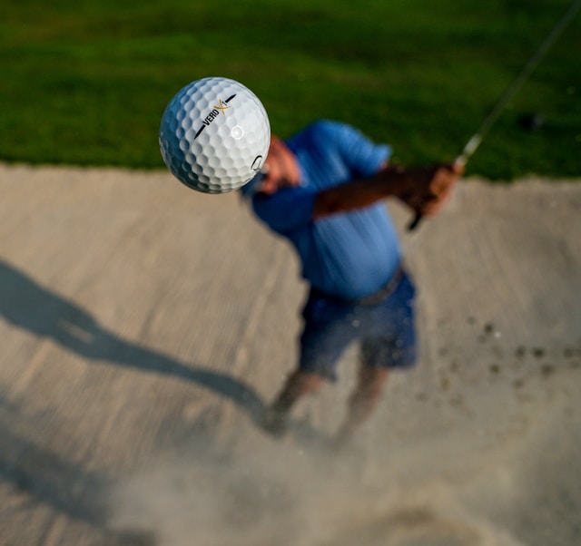 close-up-golf-ball-of-player-swinging-out-of-bunker